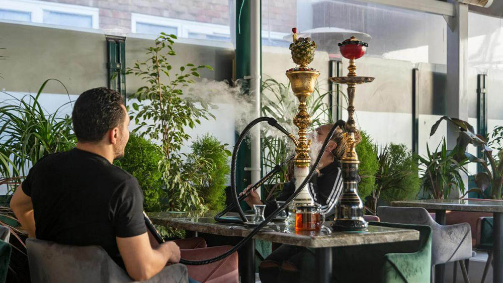 barbat care fumeaza o narghilea intr-un local